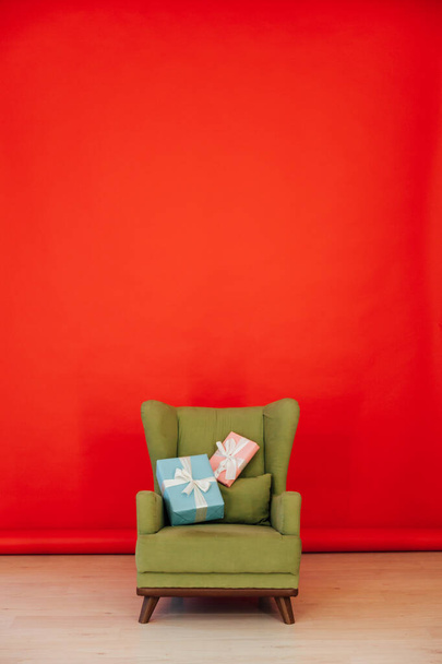 赤の部屋の中にプレゼント付きの緑のヴィンテージチェア - 写真・画像