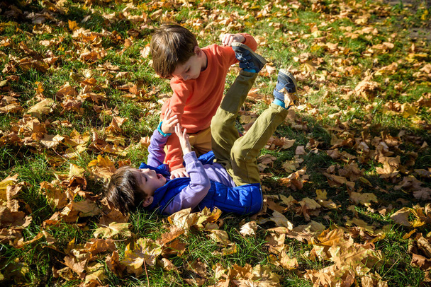 Two boys fighting outdoors. Friends wrestling in summer park. Siblings rivalry. Aggressive kid hold younger boy on ground, try to hit him - Fotoğraf, Görsel