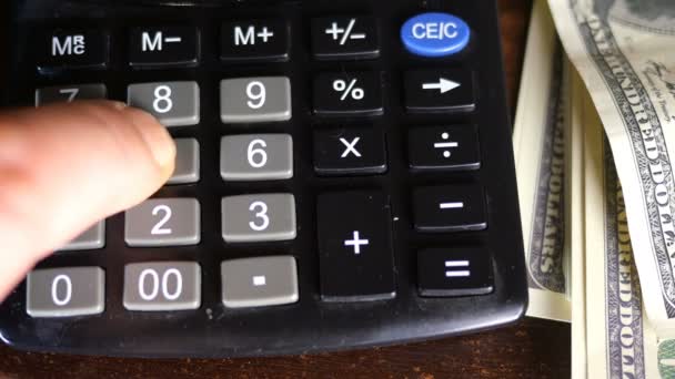 Human fingers of hand make counts of money - amerikan dollars, which lie nearby, on calculator. The concept of keeping records of home finances or business profits. - Footage, Video