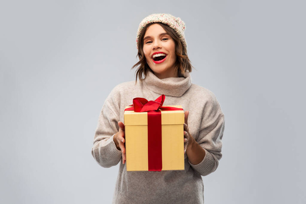 young woman in knitted winter hat holding gift box - Foto, Bild