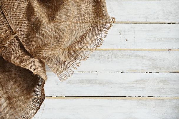 Una imagen de tela de arpillera arrugada vieja cubierta a través de una mesa de madera lavada blanca vieja
. - Foto, Imagen