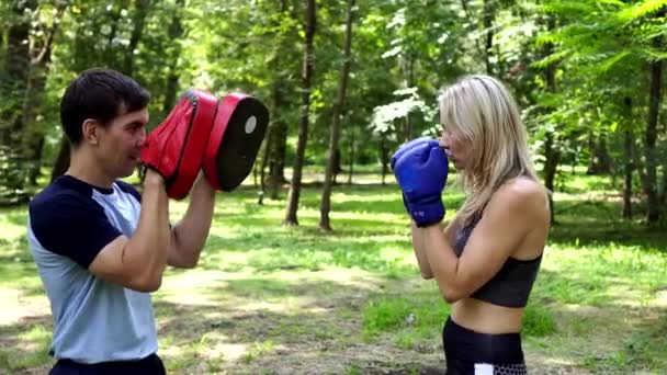 Kobieta boksuje w parku z trenerem. - Materiał filmowy, wideo
