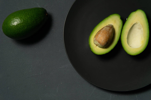 Fresh, raw avocado sliced on a black plate - Φωτογραφία, εικόνα