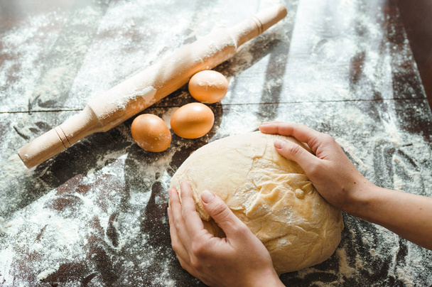 Making dough by female hands on wooden table background. Cooking concept. Lovely female hands. - 写真・画像
