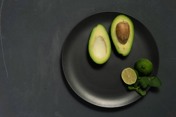 Avocado with limes on a dark backgroung - Φωτογραφία, εικόνα