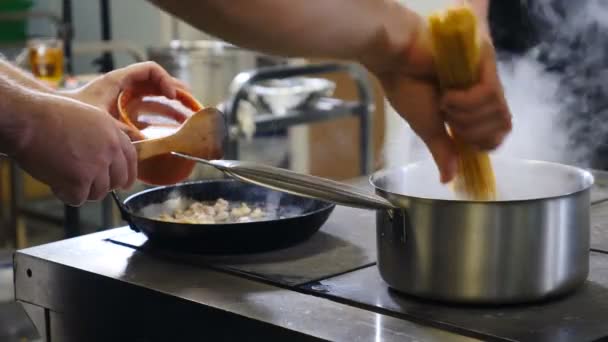 Εστιατόριο κουζίνα σπεύδουν. Κοντινό πλάνο του προσωπικού της κουζίνας απασχολημένος εργασίας: μαγείρεμα ζυμαρικά θαλασσινών. ανακατεύοντας, βάζοντας ζυμαρικά σε βραστό κατσαρολάκι. τραβηγμένο σε 4k - Πλάνα, βίντεο