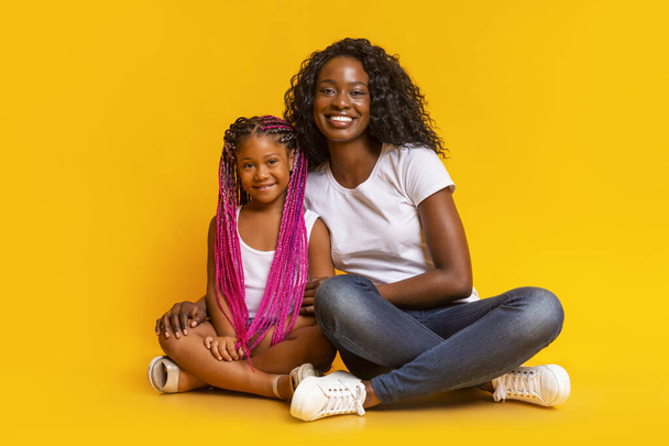 schöne schwarze Mutter sitzt auf dem Fußboden mit ihrer süßen Tochter - Foto, Bild