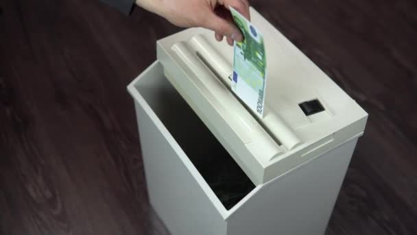 Shredder destruye un billete de cien euros. Un hombre arroja dinero a una trituradora de papel
 - Metraje, vídeo