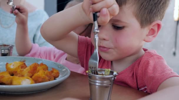 Kleine tweeling eet vork gebakken kip nuggets met saus, Jongen en meisje hebben een smakelijk diner in restaurant, Heerlijke kinderen eten bij fast food, - Video