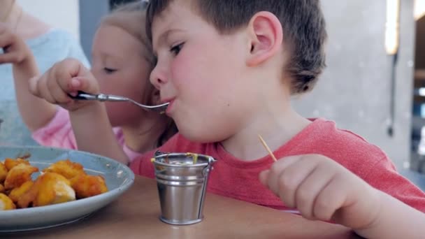 Férfi gyermek eszik villa sült csirke rögök mártással, Fiú és lány van egy étvágygerjesztő vacsora étteremben, - Felvétel, videó