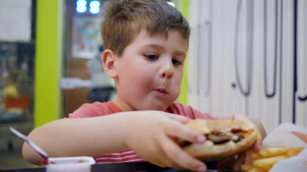 Olajos ételek az iskolai menzán ebédre, Kisfiú étvággyal eszik a kisgyermekek étteremben, Gyönyörű babaevés, - Felvétel, videó