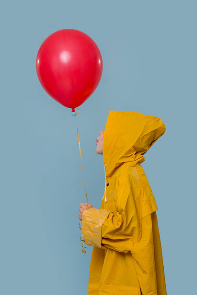Boy in a yellow raincoat with a red balloon  - Fotó, kép