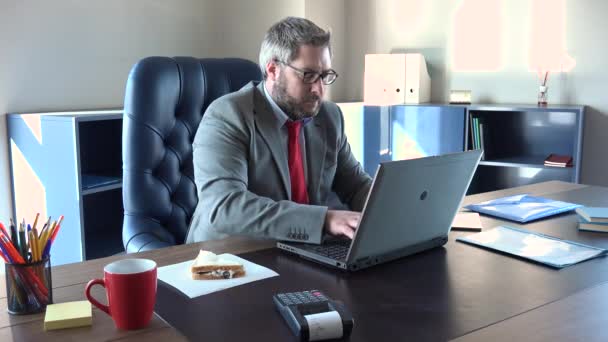Efficient businessman working quickly at office and eating sandwich, work hard under pressure to meet the deadline. Elegant director typing on computer without lunch break, stressful lifestyle - Felvétel, videó