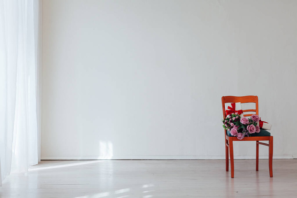 egy szék virágokkal egy fehér üres szoba belsejében - Fotó, kép