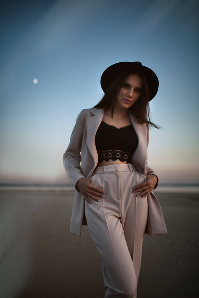 Attractive girl in suit and hat on the sunset beach - Foto, immagini