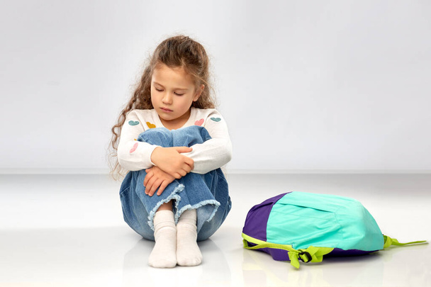sad little girl with school bag sitting on floor - Foto, immagini