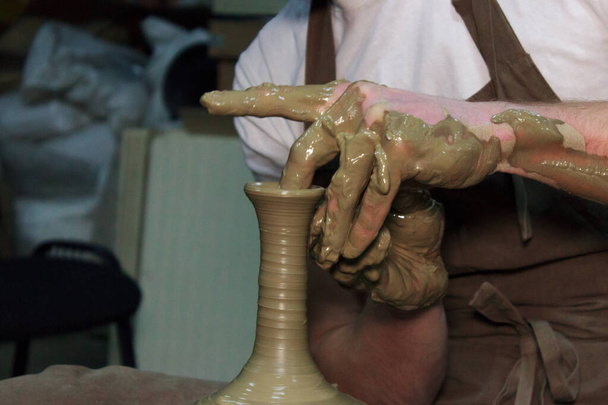 ベテランの陶芸家がろくろに大きな花瓶を作っています。首を絞めて粘土製品. - 写真・画像