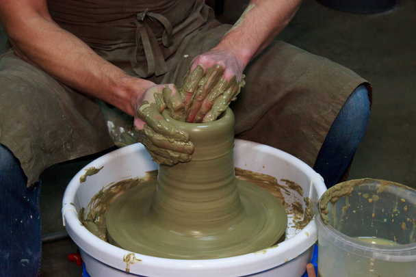 Der erfahrene Töpfer stellt eine große Vase auf einer Töpferscheibe her. Lehmprodukt. Hände eines Töpfers. Dreharbeiten für Reportagen. - Foto, Bild