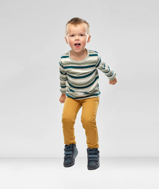 portrait of little boy in striped shirt jumping - 写真・画像