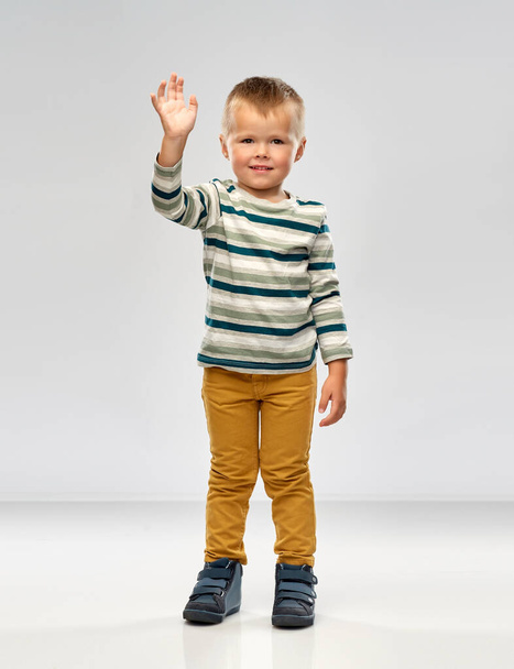 little boy in striped shirt waving hand - 写真・画像