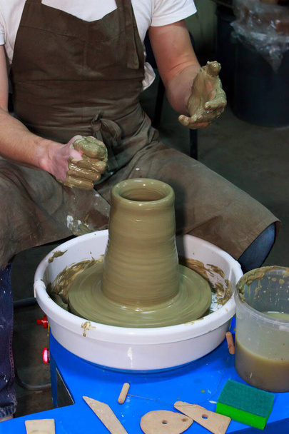 ベテランの陶芸家がろくろに大きな花瓶を作っています。粘土製品だ陶芸家の手だレポート撮影. - 写真・画像