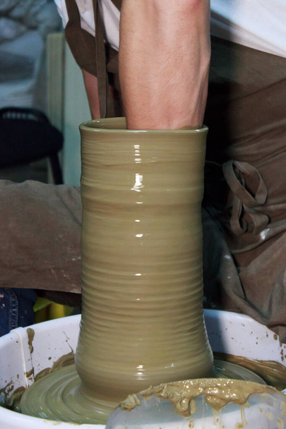 ベテランの陶芸家がろくろに大きな花瓶を作っています。粘土製品だ陶芸家の手だレポート撮影. - 写真・画像