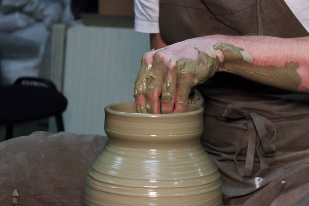 досвідчений гончар робить велику вазу на гончарному колесі. глиняний продукт. руки гончаря. репортаж зйомки
. - Фото, зображення