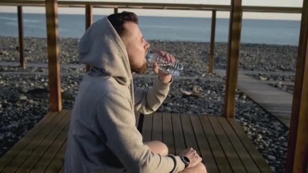 Muž uhasí žízeň s chladnou vodou po sportovním tréninku - Záběry, video