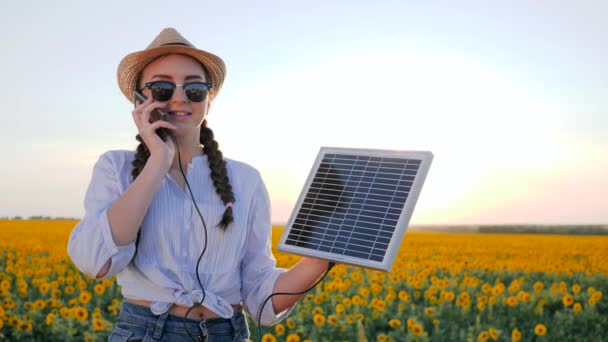 natural resources, woman in backlit talk mobile and keep solar battery tracking sun to charge battery, girl speaks by mobile - Footage, Video