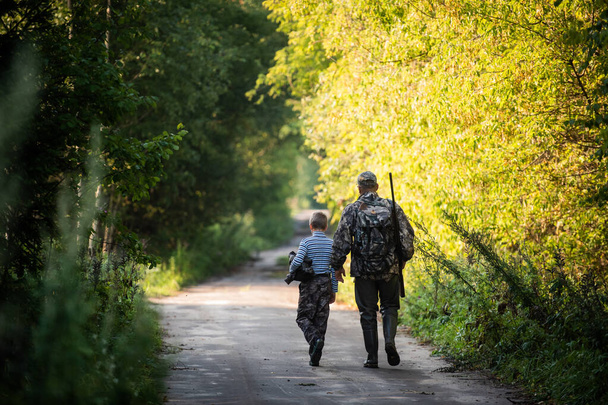 Father and son together hunting together. Walking the road in a forest. - Photo, image