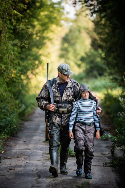 Apa az első szarvasvadászatra mutat és vezeti a fiát. - Fotó, kép