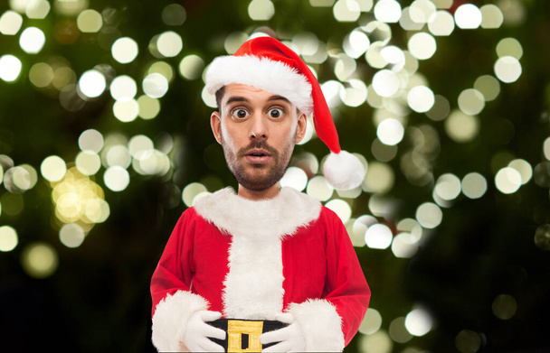 surprised man in santa costume over christmas tree - Foto, Bild