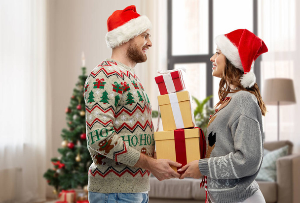 couple in christmas sweaters with gifts at home - Foto, Imagem