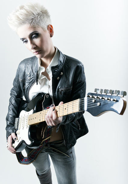 Young woman with rocker outfit and electric guitar - Fotó, kép