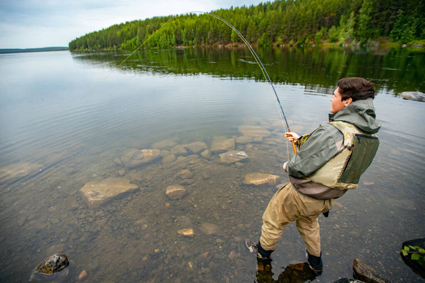 Pescador usando vara pesca com mosca no rio de montanha outono salpicando água - Foto, Imagem