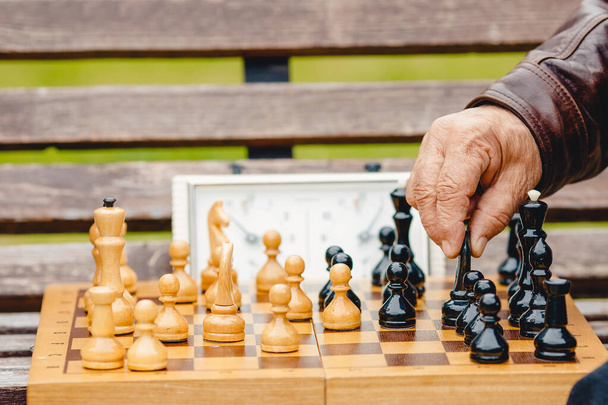 Elderly man senior holds chess piece game board outdoors - Photo, Image