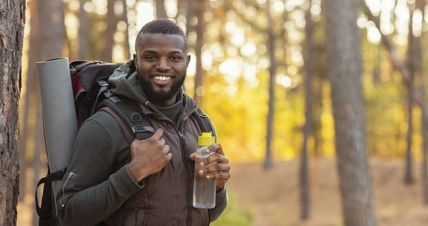 Ευτυχισμένος τύπος με σακίδιο χαμογελώντας πάνω από δάσος φόντο - Φωτογραφία, εικόνα