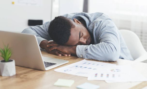 Przepracowany pracownik Afryki śpi w biurze w miejscu pracy. - Zdjęcie, obraz