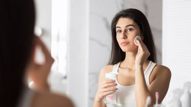 Dziewczyna przy użyciu Cotton Pad Usuwanie makijażu stojąc w łazience, Panorama - Zdjęcie, obraz