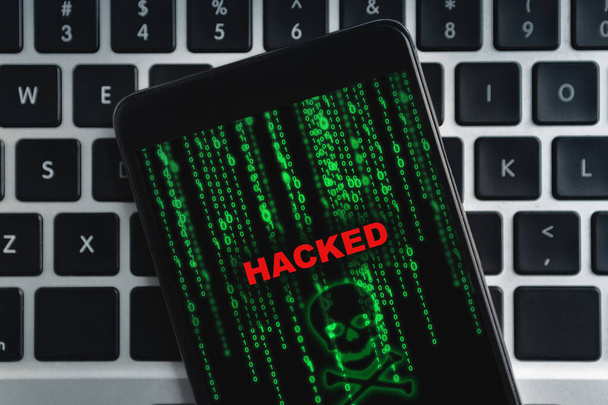 Closeup of hacked smartphone lying on laptop keyboard - Photo, Image