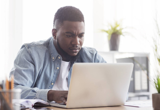 Фокусований афроамериканський працівник працює на ноутбуці в офісі
 - Фото, зображення