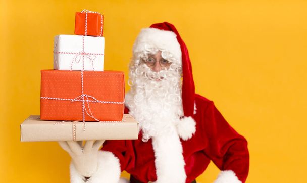 Weihnachtsmann hält Weihnachtsgeschenke in der Hand auf gelb - Foto, Bild
