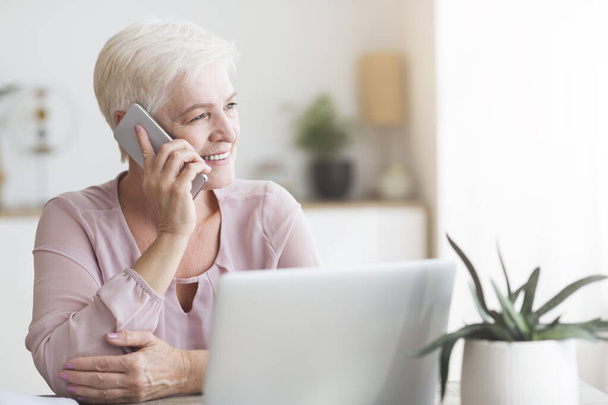 Mujer anciana positiva hablando por teléfono con los clientes
 - Foto, imagen