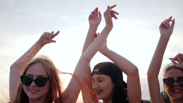 party, młode kobiety tańczą na tle lśniącego morza, dziewczyny bawią się na brzegu, letni odpoczynek o zachodzie słońca - Materiał filmowy, wideo