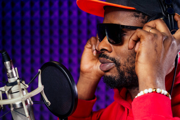 afro american man headphones in a cap and a hood sunglasses recording hip hop song track. - Photo, image
