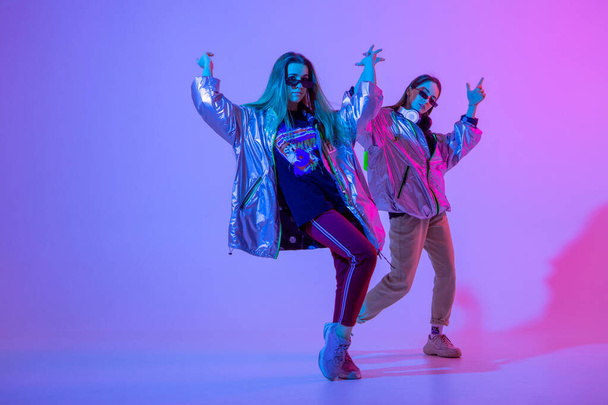 Young stylish girls dancing in the Studio on a colored neon background. Music dj poster design. - Foto, immagini