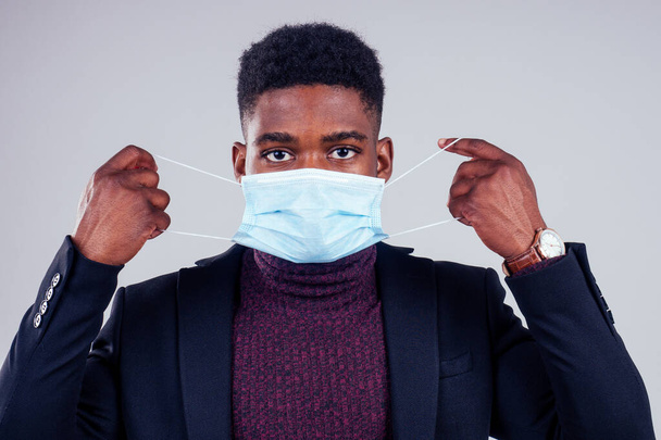 African american male wearing on a gauze mask and warm coat and sweater white background studio. cold season winter autumn or spring. - Fotografie, Obrázek