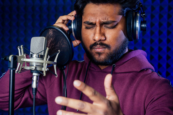 professional singing indian men headphones sound modern studio violet background recording song. - Фото, изображение