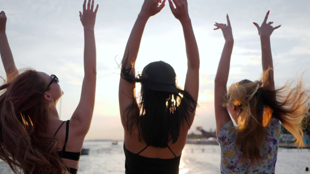 Lebensfreude, Glück junge Frauen tanzen auf Hintergrund glänzendem Meer im Urlaub, Mädchen haben Spaß am Damm, beste Freundinnen tanzen - Filmmaterial, Video