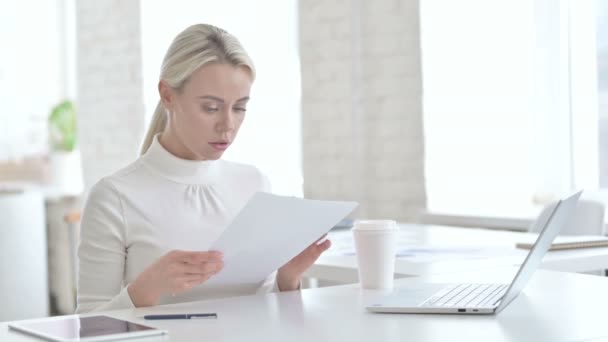 Jonge zakenvrouw die documenten leest in het moderne kantoor - Video